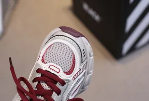 Detailed close-up of grey breathable mesh and silver synthetic leather stitching on sneakers