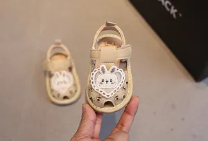 Dettaglio dei sandali beige per neonata con toppa a coniglio e pizzo a forma di cuore