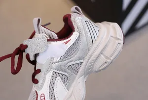 Detail of kids breathable mesh sneaker with cream and red panels and velcro strap
