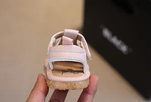 Dettaglio del sandalo rosa per neonati con linguetta sul tallone e suola in gomma antiscivolo