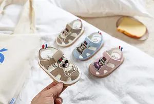 Détail de sandales pour bébé avec motif d'ours, fermeture velcro et semelles en caoutchouc
