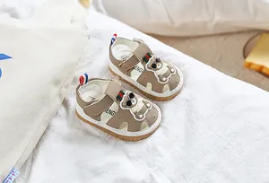 Gros plan de sandales pour bébé avec décor d'ours et sangles velcro rayées