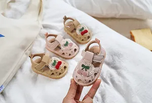 Detail of baby girl sandals featuring cherry embroidery and heart lace on soft soles