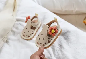Détail de sandales pour bébé fille avec fleurs orange tricotées et motifs à pois