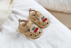 Close-up of baby girl sandals featuring lace heart edges and embroidered cherries