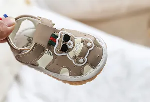 Détail d'une sandale pour bébé avec écusson ours et semelle souple antidérapante