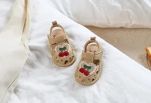 Detail of baby girl leather sandals featuring cherry ornaments and heart lace patterns