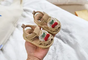Detail of beige baby sandals with lace heart trim and red crochet cherry patterns