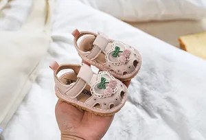 Detail of pink baby sandals with sequin cherry embroidery and lace heart accents