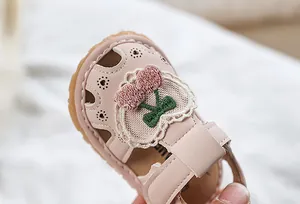 Close-up of pink baby sandal featuring cherry embroidery and heart-shaped cutouts