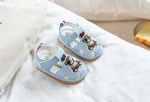 Détail de sandales bébé bleu clair avec décor ours et bride velcro sur tissu doux