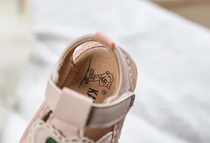 Close-up of baby girl pink leather sandals with cartoon insoles and detailed stitching