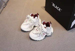 Top view of white and burgundy mesh sneakers with velcro straps on a grey floor