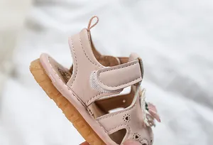 Detail of pink baby sandals featuring heart cutouts and a soft rubber sole for toddlers