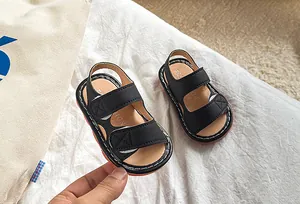 Vue détaillée de sandales noires pour bébé en cuir avec velcro et coutures blanches