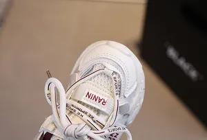 Close-up of kids' white sneakers showing mesh texture, burgundy details and logo laces