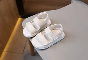 Dettaglio di sandali bianchi per bambini con cinturini a strappo e suola antiscivolo