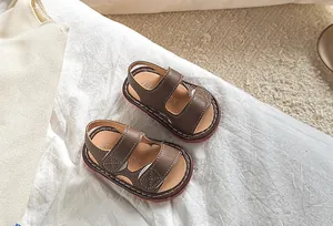 Détail de sandales en cuir marron foncé pour bébé avec coutures blanches et semelles