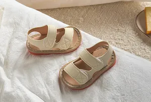 Gros plan de sandales bébé beige avec scratchs, coutures en X et semelle marron antidérapante