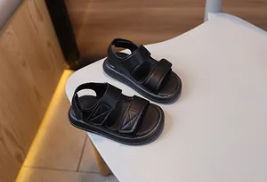Dettaglio di sandali neri per bambini con doppia chiusura a strappo su sedia bianca