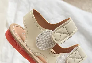 Détail de sandales bébé beige avec semelle orange antidérapante et fermeture velcro