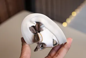 Close-up of flexible white baby sandal sole showing softness and bendability