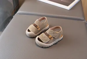 Detail von Baby-Sandalen aus beigem Kunstleder mit doppeltem Klettverschluss und Zehenschutz