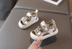 Detail der geschlossenen Babysandale mit gestepptem Gittermuster und Bären-Abzeichen