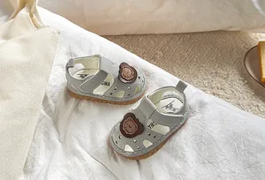 Detail of baby boy summer sandals with star cutouts and a cute brown bear patch