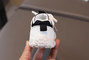 Detail of breathable mesh and slip-resistant thick sole on kids' black and white sneakers