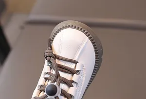 Macro detail of toddler boots showing white textured leather and protective gum sole toe
