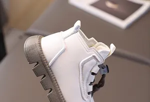 Detail of off-white faux leather kids boots with anti-slip rubber soles and pull tabs