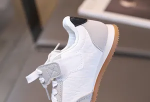 Dettaglio di scarpe sportive per bambini con cuciture in pelle e suola antiscivolo