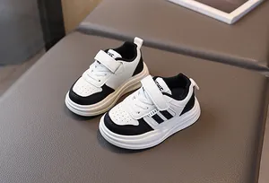 Gros plan de baskets pour enfants noir et blanc avec bande velcro et détails en cuir perforé