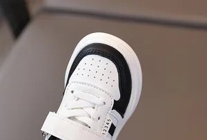 Détail de baskets enfant montrant le bout en cuir blanc perforé et renforts noirs