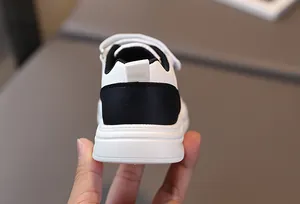 Gros plan des baskets blanches pour enfants avec talon noir contrasté et languette arrière