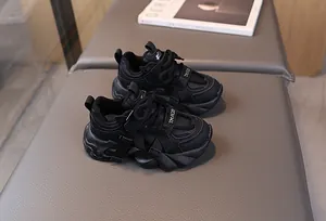 Detail shot of black chunky kids sneakers with hook and loop strap and non-slip sole