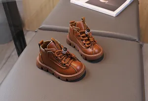 Detail view of brown leather kids martin boots featuring classic laces and rubber soles