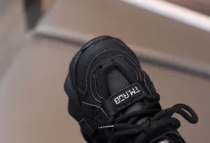 Macro shot of breathable mesh and synthetic leather texture on black kids' sneakers