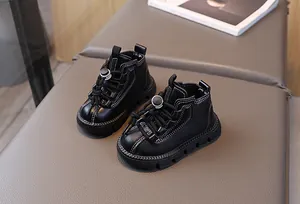 Close-up of black leather kids boots featuring white contrast stitching and bungee laces