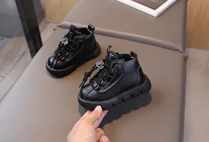 Detail of black leather kids' boots with contrast stitching and adjustable toggle closure