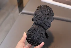 Detailed view of the deep non-slip groove design on the black children sneaker sole