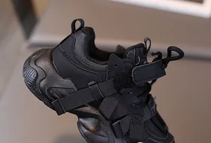 Detail of all-black kids' sneaker with mesh texture, velcro strap and anti-slip thick sole