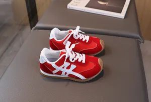 Dettaglio di scarpe rosse per bambini su panca grigia con trama scamosciata e suola in gomma