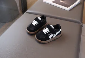 Detail of kids black leather fashion sneakers with velcro strap and gum rubber sole