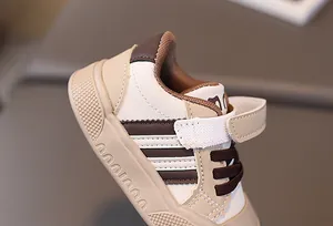 Detailed close-up of beige baby sneakers showing Velcro straps and brown stripes