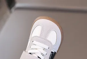 Detail view of children's suede trainer shoes with a serrated U-shaped toe and gum sole