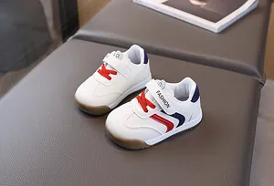 Detail of white kids sneakers with red and blue stripes and non-slip rubber sole