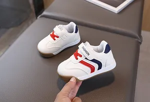 Detail of white leather kids sneaker with red laces and non-slip gum rubber sole