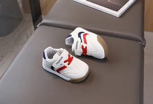 Top view of white toddler sneakers with red laces and non-slip gum rubber soles